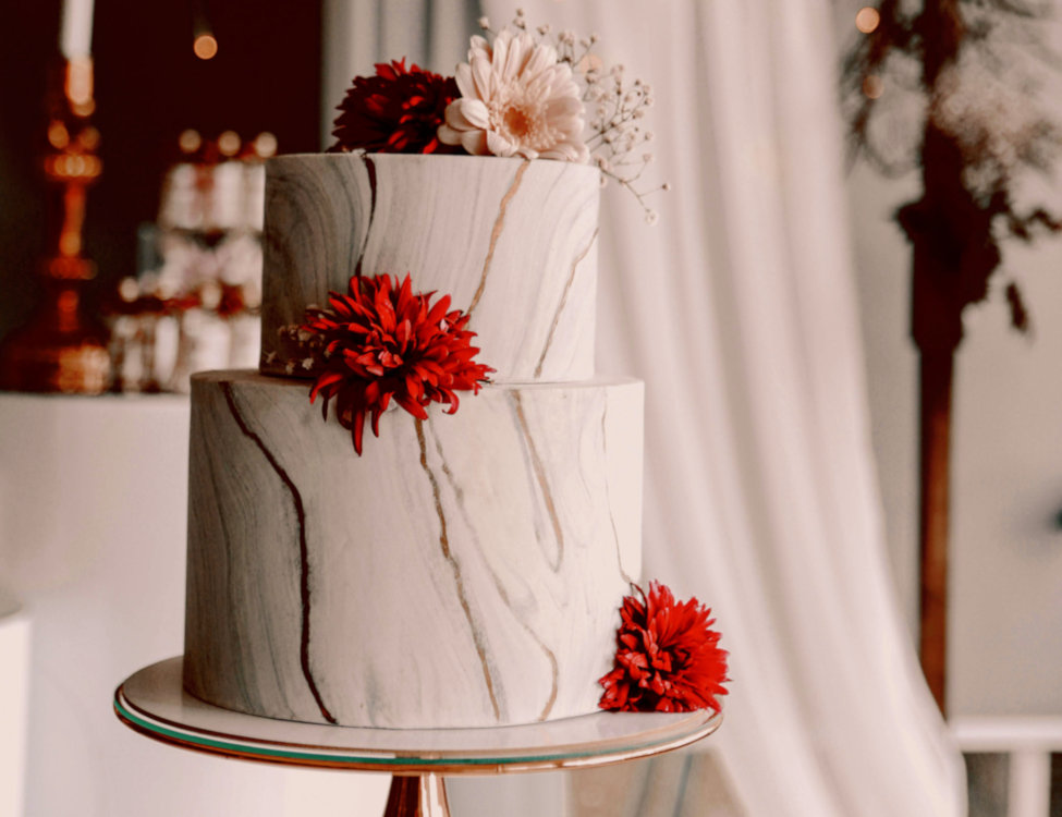 Two tier wedding cake with flowers and a golden marble effect.